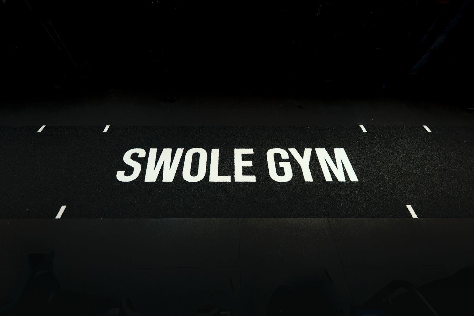 The Swole Gym lifting platform, its name printed across the black rubber floor